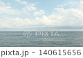 晴朗的天空和潔白的雲朵橫跨平靜廣闊的海洋地平線。 140615656