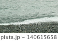 特寫鏡頭展現了海浪拍打海岸和陰天海灘上的鵝卵石。 140615658