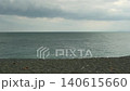 平靜的海岸線是由平靜多雲的大海和綿延至地平線的厚厚雲層共同創造的。 140615660