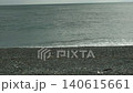 陰天裡，輕柔的海浪拍打著鵝卵石海灘，形成一片白色的泡沫狀退潮景象。 140615661
