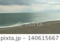 白色的波浪在陰雲密佈的天空下輕輕拍打著海岸線，浩瀚的海洋盡收眼底。 140615667