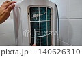 Male technician cleaning air conditioner indoors. Washing and cleaning the heat exchanger coils of an air conditioner outside. 140626310