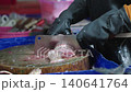 Fishmonger cutting fresh fish for customer at seafood market. Authentic seafood trade and daily life at a traditional wet market in Thailand 140641764