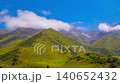 Time-lapse of cows grazing in green mountain slopes of Kyrgyzstan under white clouds flowing above 140652432