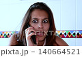 Surprised young woman with wide eyes talking on the phone, her expression changing from shock and disbelief to happiness and relief upon receiving amazing news in slow motion 140664521