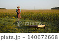Farmer juggling cornhole bags in corn field, wide shot. Man taking break during work in agricultural business and warming up before popular American outdoor game, training coordination and balance. 140672668