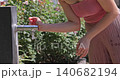 Woman refreshing face with water from public fountain 140682194