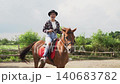 Smiling woman riding horse through sunny rural paddock in calm forward motion 140683782