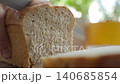 Hand cuts soft bread slice with knife. Concept of bread preparation 140685854