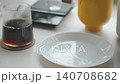 Hand placing chocolate muffin on plate beside glass of coffee 140708682