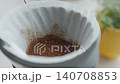 Hot water pours over ground coffee inside paper filter in coffee dripper 140708853