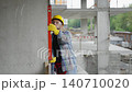 Construction worker using spirit level to check concrete wall 140710020