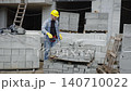 Construction worker moving concrete cinder blocks 140710022