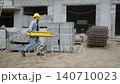 Construction worker carrying heavy wooden beam at site 140710023