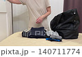 Women organizing clothes, Person meticulously categorizing clothing items before packing them away, Woman carefully sorting and comparing shirts and trousers before placing them into bag 140711774