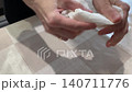 Woman extracts splinter. Woman carefully removes finger splinter. Caucasian lady delicately plucks tiny splinter from finger. Closeup of woman removing tiny splinter from finger with tissue and care 140711776