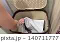 Laundry towel retrieved, Neatly arranged towel presented from woven hamper in bathroom corner, Scene depicting tidy organization with towel lifted from woven laundry basket in bathroom corner 140711777