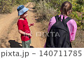 Children exchanging cheerful expressions in nature, Young siblings engaging joyfully along forest pathway, Two young children sharing happy moments while exploring wooded outdoor trail 140711785