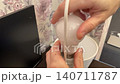 Homeowner replaces light. Replacing lamp bulb carefully today. Closeup shows fingers guiding new light into fixture. Individual gently tightens LED bulb into socket ensuring proper connection 140711787