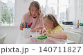 Close-up of tattooed hands holding a small colorful object in a sunlit room 140711827