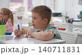 Close-up of tattooed hands holding a small colorful object in a sunlit room 140711831