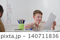 Close-up of tattooed hands holding a small colorful object in a sunlit room 140711836