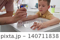 Close-up of tattooed hands holding a small colorful object in a sunlit room 140711838