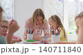 Close-up of tattooed hands holding a small colorful object in a sunlit room 140711840