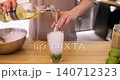 Alcohol pouring. Mojito making. Unrecognizable barman hand preparing classic beverage using measuring tool into glass with crushed ice lime at workplace. 140712323