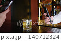 Cocktail photo. Smartphone using. Unrecognizable people hands taking picture of modern alcohol beverage in transparent glass on bar counter. 140712324