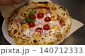 Garnishing pizza. Pizzaiolo serving. Unrecognizable chef hand adding fresh toppings basil leaves cherry tomatoes shrimp for dish in cafeteria. 140712333