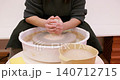 Pottery craft. Handmade occupation. Unrecognizable professional female artisan hands forming raw clay using wheel in workplace. 140712715