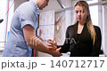 Arm rehabilitation. Kinesiologist therapy. Physical trainer man assisting woman patient at professional workspace indoor. 140712717