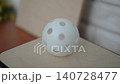 Pickleball ball rolls over surface of paddle closeup. Hollow white ball with holes balances on paddle and rolls from edge to edge. 140728477
