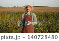 Caucasian man in work clothes against cornfield holds bean bags for cornhole game in hands. Farmer on break with active game accessories in front of camera. 140728480