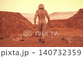 Lone Astronaut Walking Across Cinematic Orange Martian Desert Landscape 140732359