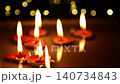 Multiple small candles placed on a dark reflective surface in the dark. 140734843