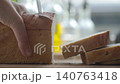 Hand slicing bread with knife, cutting thick pieces from a loaf 140763418