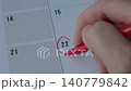 Female hand using a red marker to circle a date on a desk calendar or planner. Appointment or event planning or reminder concept 140779842