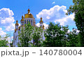 Timelapse of white clouds drifting over the golden domes of an Orthodox church against a bright blue sky. Peaceful religious architecture, spiritual landmark, and scenic outdoor view with moving cloud 140780004
