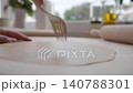 Hand pricks rolled dough with fork on kitchen counter 140788301