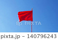 red flag flutters in wind against sky 140796243