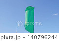 green flag flutters in wind against sky 140796244