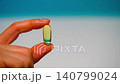 Hand of woman, girl holds golden capsule with Omega 3 on light background. Vitamins 140799024