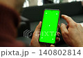 Hand of young man holding smartphone green screen in business office work. Mobile phone vertical mockup. Male person using phone with blank green background display. Chroma key smart phone. Close up. 140802814