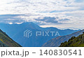 Time lapse of clouds moving over layered mountain range in Kyrgyzstan with sun rays breaking through. Camera pans left, showing slopes, ridges, and green vegetation. 140830541