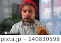 A man enjoying a fresh croissant for breakfast and using his smartphone 140830598