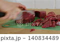 A housewife cuts beef on a cutting board. Close-up of hands with a knife cutting meat. Healthy eating. Preparing a raw beef steak for a family dinner. Handling raw meat. Cooking. Homemade food. 140834489