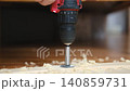 Close-up of electric drill making hole in wooden board. Clean woodworking scene. Natural light. Detailed wood texture. DIY project, craft, construction, home improvement. Copy space. slow motion 140859731