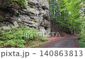 Walking through a forest trail in Hruba Skala, Bohemian Paradise (Cesky raj), Czech Republic. Towering sandstone rock formations line the path in one of the country's most popular hiking destinations. 140863813